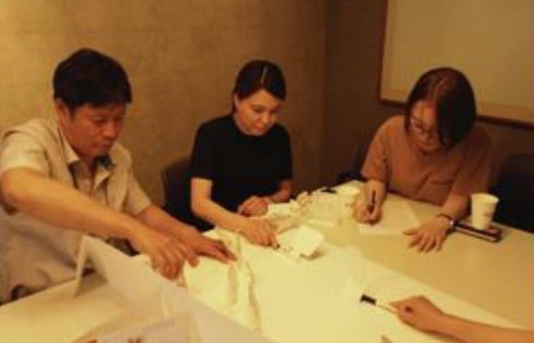 テーブルの周りに集まっている人たち 中程度の精度で自動的に生成された説明