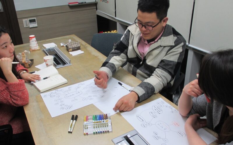 デスクの上に座っている男性 低い精度で自動的に生成された説明